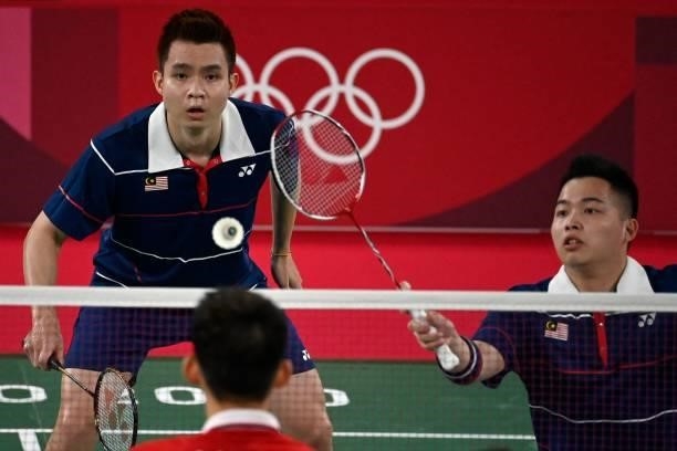 Malaysia's Aaron Chia hits a shot next to Malaysia's Soh Wooi Yik in their men's doubles badminton semi-final match against China's Liu Yuchen and...