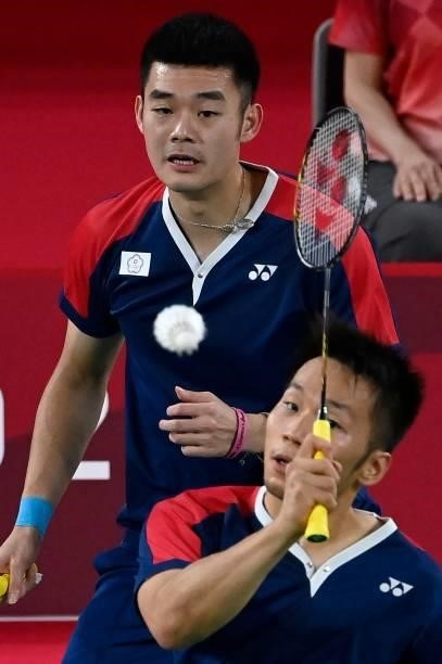 Taiwan's Lee Yang hits a shot next to Taiwan's Wang Chi-lin in their men's doubles badminton semi-final match against Indonesia's Mohammad Ahsan and...