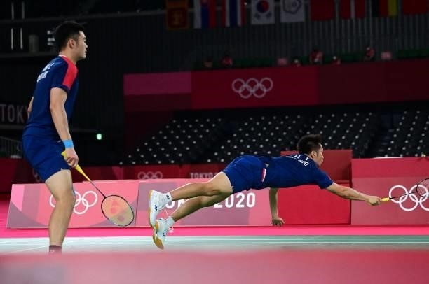 Taiwan's Lee Yang dives for a shot next to Taiwan's Wang Chi-lin in their men's doubles badminton semi-final match against Indonesia's Mohammad Ahsan...
