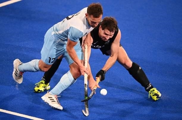 Argentina's Lucas Martin Vila is tackled by New Zealand's David Brydon during their men's pool A match of the Tokyo 2020 Olympic Games field hockey...