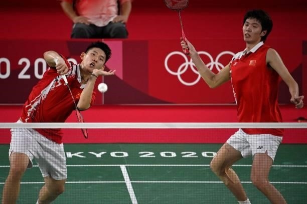 China's Liu Yuchen hits a shot next to China's Li Junhui in their men's doubles badminton semi-final match against Malaysia's Soh Wooi Yik and...