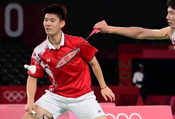 China's Li Junhui hits a shot next to China's Liu Yuchen in their men's doubles badminton semi-final match against Malaysia's Soh Wooi Yik and...