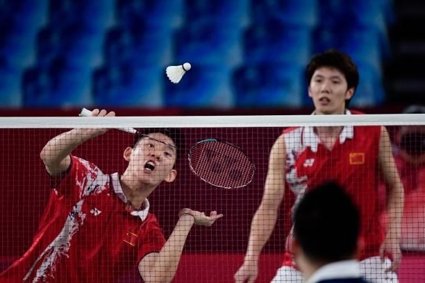 China's Liu Yuchen hits a shot next to China's Li Junhui in their men's doubles badminton semi-final match against Malaysia's Soh Wooi Yik and...