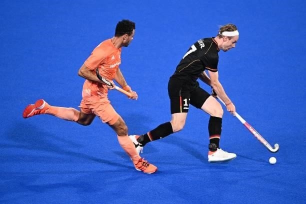 Germany's Jan Christopher Ruhr dribbles the ball as Netherlands' Glenn Schuurman runs behind him during their men's pool B match of the Tokyo 2020...