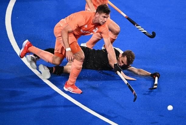 Netherlands' Jorrit Croon and Germany's Timm Alexander Herzbruch fall during their men's pool B match of the Tokyo 2020 Olympic Games field hockey...