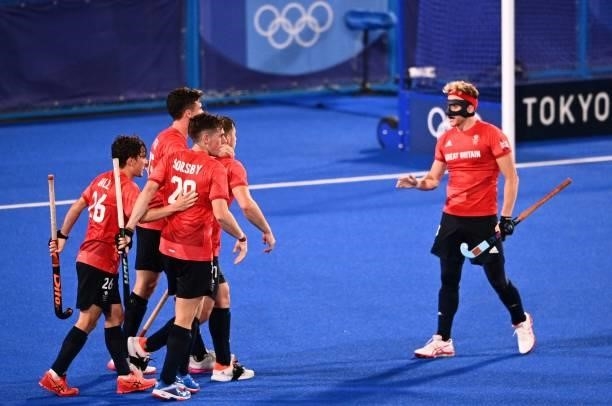Players of Britain celebrate after scoring against Belgium during their men's pool B match of the Tokyo 2020 Olympic Games field hockey competition,...