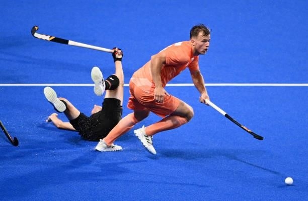 Netherlands' Thijs Johannes Reinier Van Dam carries the ball next to a fallen player of Germany during the men's pool B match of the Tokyo 2020...