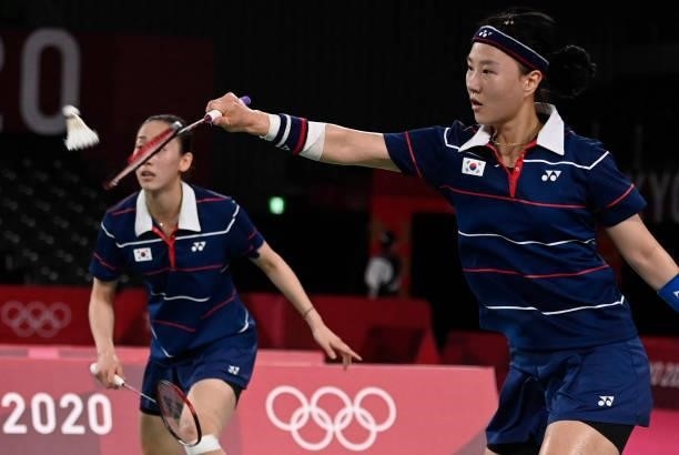 South Korea's Shin Seung-chan hits a shot next to South Korea's Lee So-hee in their women's doubles badminton semi-final match against Indonesia's...