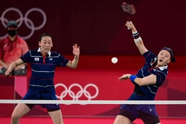 South Korea's Shin Seung-chan hits a shot next to South Korea's Lee So-hee in their women's doubles badminton semi-final match against Indonesia's...