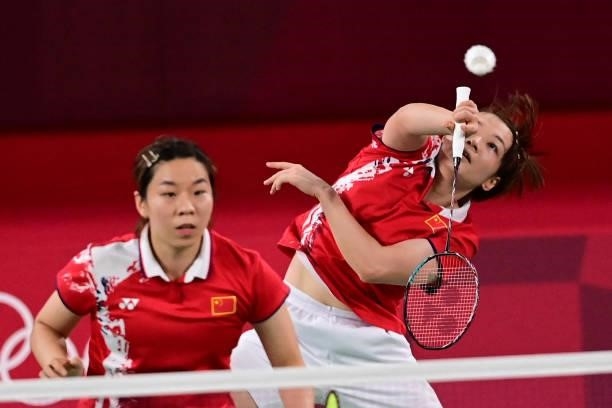 China's Chen Qingchen hits a shot next to China's Jia Yifan in their women's doubles badminton semi-final match against South Korea's Kong Hee-yong...