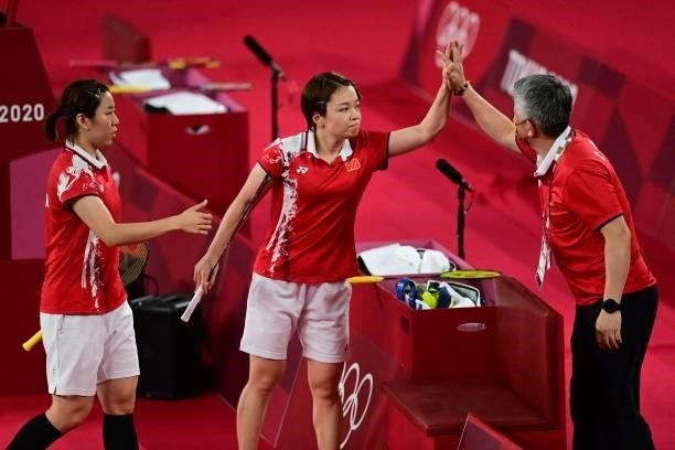 China's Chen Qingchen and China's Jia Yifan celebrate with a coach after winning their women's doubles badminton semi-final match against South...