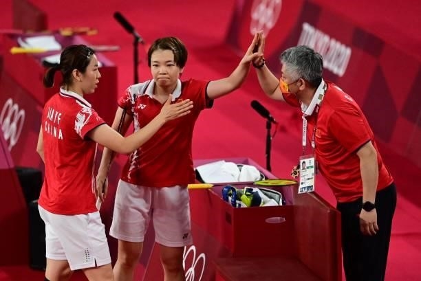 China's Chen Qingchen and China's Jia Yifan celebrate with a coach after winning their women's doubles badminton semi-final match against South...