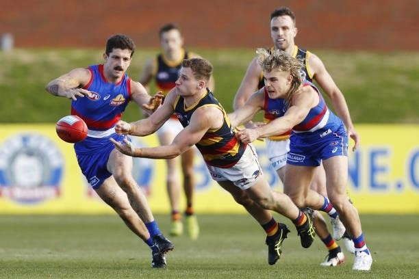 Rory Laird of the Crows handpasses the ball as he is tackled by Tom Liberatore of the Bulldogs and Bailey Smith of the Bulldogs during the 2021 AFL...