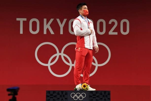 China's Lyu Xiaojun poses with his gold medal on the podium for the victory ceremony of the men's 81kg weightlifting competition during the Tokyo...