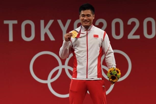 China's Lyu Xiaojun poses with his gold medal on the podium for the victory ceremony of the men's 81kg weightlifting competition during the Tokyo...