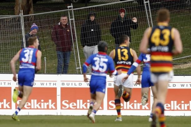 Fans watch on from the other side of the fence during the 2021 AFL Round 20 match between the Western Bulldogs and the Adelaide Crows at Mars Stadium...