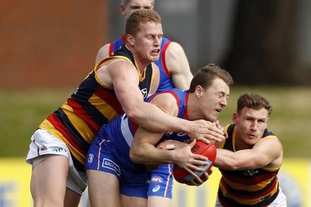 Jack Macrae of the Bulldogs is tackled by Reilly OBrien of the Crows and Rory Laird of the Crows during the 2021 AFL Round 20 match between the...