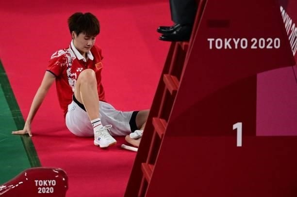 China's Chen Yufei sits on the floor as she is seen by a medic during her women's singles badminton semi-final match against China's He Bingjiao...