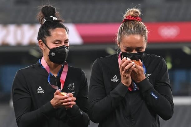 New Zealand player kisses her gold medal through her face mask as they celebrate on the podium for the victory ceremony after the women's final rugby...