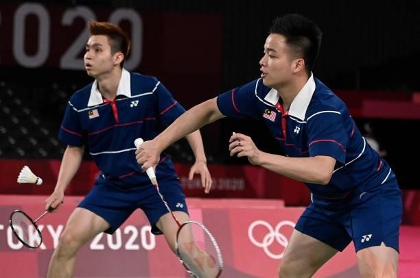 Malaysia's Aaron Chia hits a shot next to Malaysia's Soh Wooi Yik in their men's doubles badminton bronze medal match against Indonesia's Mohammad...