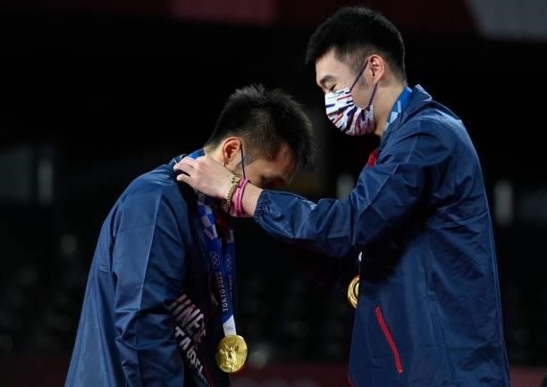 Taiwan's Lee Yang is given his gold medal by partner Taiwan's Wang Chi-lin after winning the men's doubles badminton event during the Tokyo 2020...