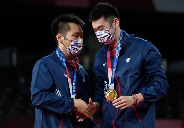 Taiwan's Lee Yang shakes hands with Taiwan's Wang Chi-lin with their men's doubles badminton gold medals at a ceremony during the Tokyo 2020 Olympic...