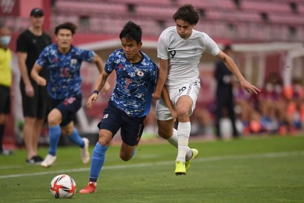 Takefusa Kubo of Japan dribbles the ball under the puressure from Matthew Garbett of New Zealand during the Men's Quarter Final match on day eight of...