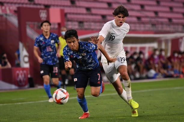 Takefusa Kubo of Japan dribbles the ball under the puressure from Matthew Garbett of New Zealand during the Men's Quarter Final match on day eight of...