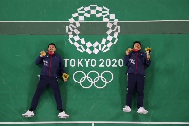 Taiwan's Lee Yang and Taiwan's Wang Chi-lin pose on the court with their men's doubles badminton gold medals during the Tokyo 2020 Olympic Games at...