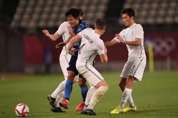 Takefusa Kubo of Japan dribbles the ball under the puressure from Nando Pijnaker and Elijah Just of New Zealand during the Men's Quarter Final match...