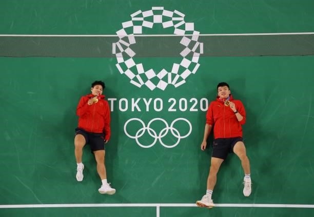China's Wang Yilyu and China's Huang Dongping pose on the court with their mixed doubles badminton gold medals during the Tokyo 2020 Olympic Games at...