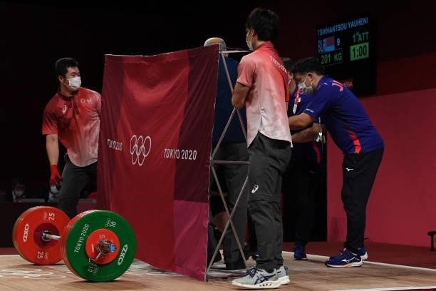 Japan's Toshiki Yamamoto receives treatment behind a screen during the men's 96kg weightlifting competition during the Tokyo 2020 Olympic Games at...