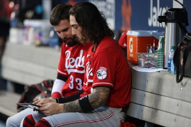 Jesse Winker of the Cincinnati Reds and Jonathan India look at a tablet during the game between the Cincinnati Reds and the New York Mets at Citi...