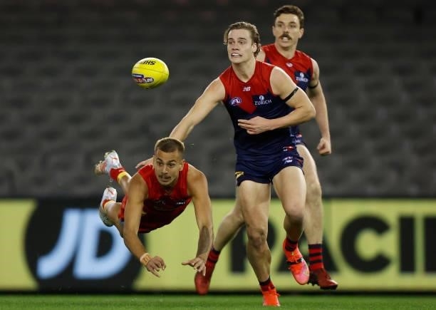 Joel Jeffrey of the Suns handpasses the ball ahead of Trent Rivers of the Demons during the 2021 AFL Round 20 match between the Gold Coast Suns and...