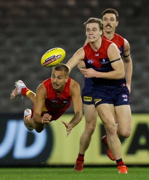 Joel Jeffrey of the Suns handpasses the ball ahead of Trent Rivers of the Demons during the 2021 AFL Round 20 match between the Gold Coast Suns and...