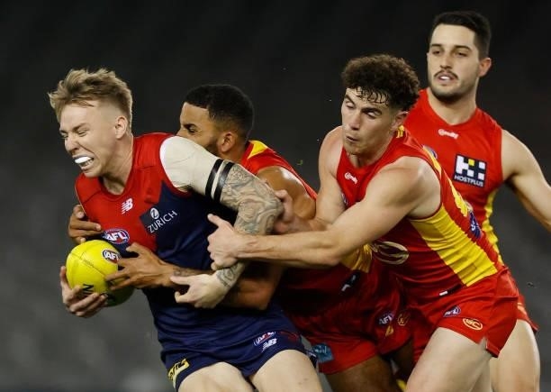 James Harmes of the Demons is tackled by Touk Miller and Sam Flanders of the Suns during the 2021 AFL Round 20 match between the Gold Coast Suns and...