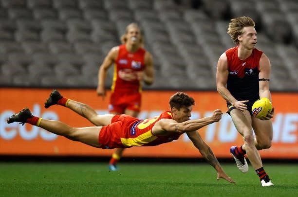 Charlie Spargo of the Demons evades Sean Lemmens of the Suns during the 2021 AFL Round 20 match between the Gold Coast Suns and the Melbourne Demons...