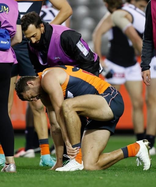 Sam J. Reid of the Giants holds his ankle during the 2021 AFL Round 20 match between the GWS Giants and the Port Adelaide Power at Marvel Stadium on...