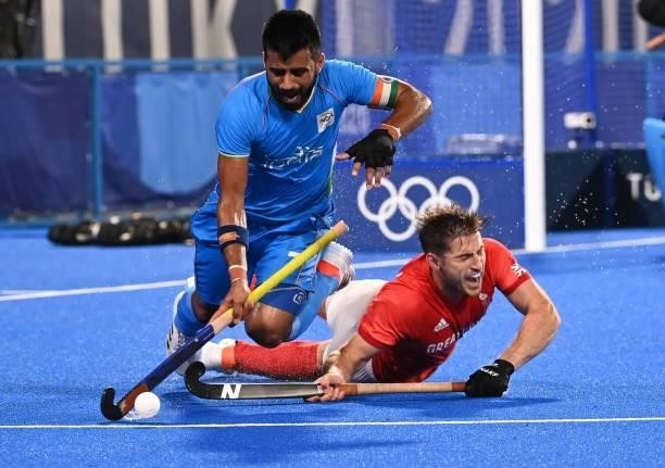 Britain's Liam Paul Ansell falls as he vies for the ball with India's Manpreet Singh during their men's quarter-final match of the Tokyo 2020 Olympic...