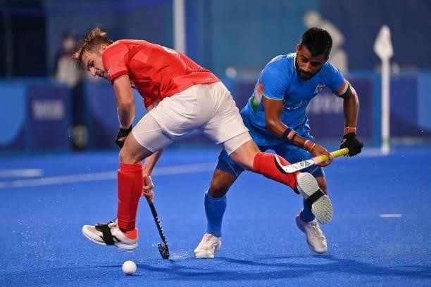 Britain's Liam Paul Ansell and India's Manpreet Singh vie for the ball during their men's quarter-final match of the Tokyo 2020 Olympic Games field...