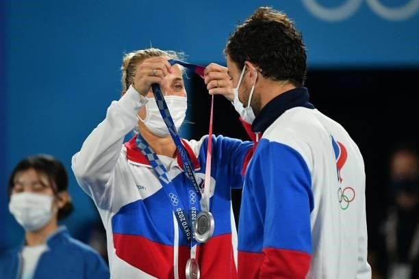 Silver medallists Russia's Elena Vesnina and Russia's Aslan Karatsev put on their respective medal during the Tokyo 2020 Olympic mixed doubles tennis...