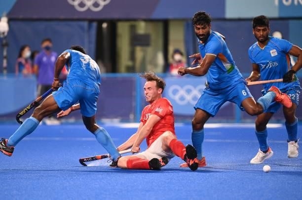 Britain's Christopher Griffiths falls between India's Amit Rohidas and Surender Kumar during their men's quarter-final match of the Tokyo 2020...