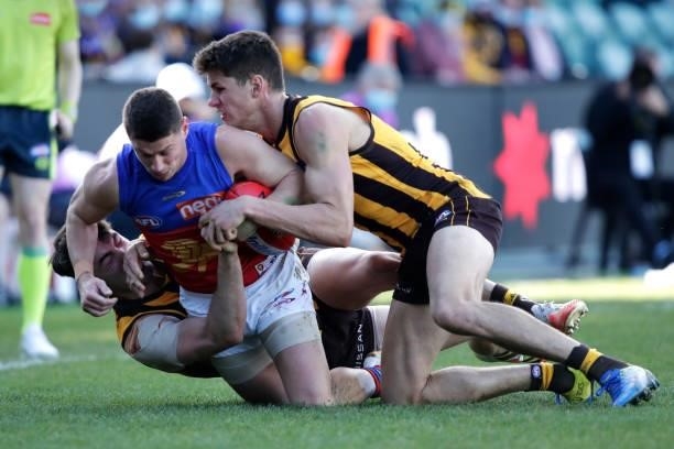 Dayne Zorko of the Lions is tackled by Conor Nash of the Hawks and Daniel Howe of the Hawks during the 2021 AFL Round 20 match between the Hawthorn...