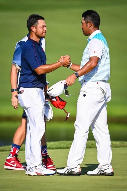 Xander Schauffele of Team USA is greeted by Hideki Matsuyama of Team Japan after winning the gold medal on the 18th hole green during the final round...