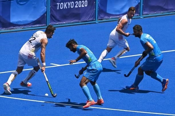 Belgium's Simon Pierre Gougnard is challenged by India's Surender Kumar and Rupinder Pal Singh during their men's semi-final match of the Tokyo 2020...