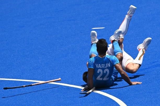 India's Varun Kumar and Belgium's Cedric Daniel Andre Charlier fall during their men's semi-final match of the Tokyo 2020 Olympic Games field hockey...