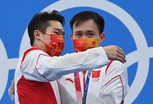 Silver medallist China's Wang Zongyuan hugs Gold medallist China's Xie Siyi as they pose with their medals on the podium after the men's 3m...