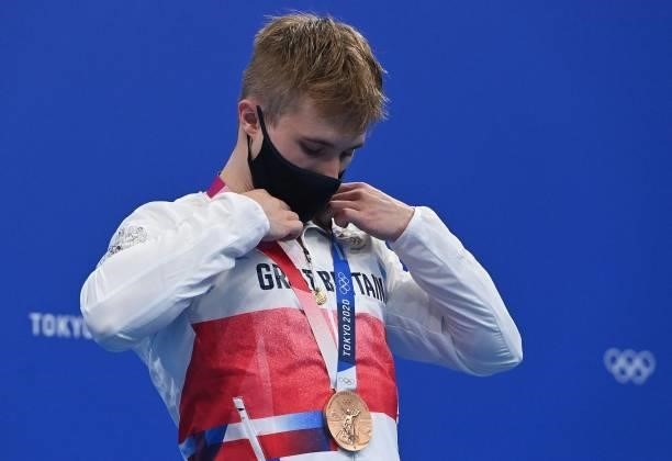 Bronze medallist Britain's Jack Laugher places his medal around his neck after the men's 3m springboard diving final event during the Tokyo 2020...