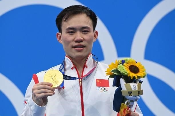 Gold medallist China's Xie Siyi poses with their medal on the podium after winning the men's 3m springboard diving final event during the Tokyo 2020...
