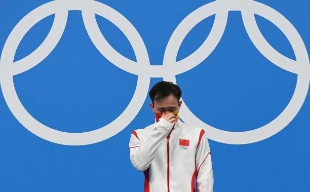 Gold medallist China's Xie Siyi reacts as he steps up to the podium after winning the men's 3m springboard diving final event during the Tokyo 2020...